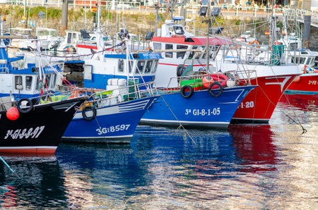 Several vibrant fishing boats are moored side by side in a lively harbor, reflecting on calm water. Perfect image for themes of maritime industry and coastal lifestyle.の写真素材