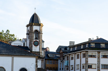 Charming old clock tower rises above rooftops in a peaceful European village at sunset, capturing classic architecture and tranquil cityscape.の写真素材