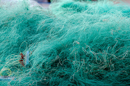 Detailed view of a traditional fishing net, showing tangled nylon threads at a harbor. Texture background highlights the busy life of fishermen and marine industry.の写真素材