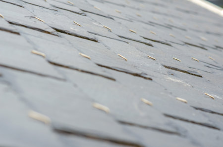 Close-up view of a traditional slate roof with visible metal hooks, illustrating durable roofing...