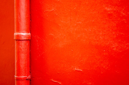 Bright red metal pipe on an abstract textured wall, perfect for backgrounds or design projects....