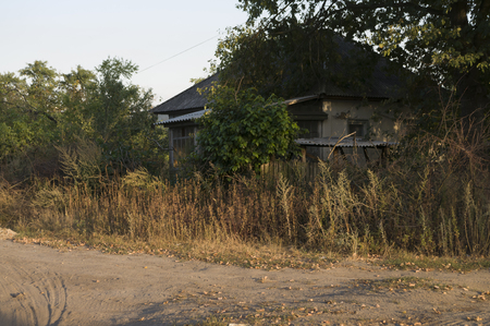 Forgotten old building in little suburb. Early fall trees of green and tint of yellow colorsの写真素材