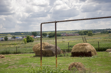 Heavy gray clouds in the cold autumn. Hayfield. There are many stacks around. Traveling on the suburb roadsの写真素材