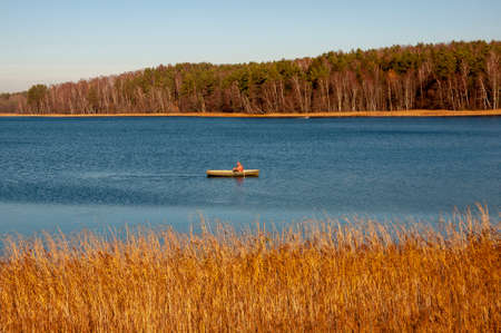 Blue river slow flowing across the fall forest with reflections of trees such as pine, birch, larch...