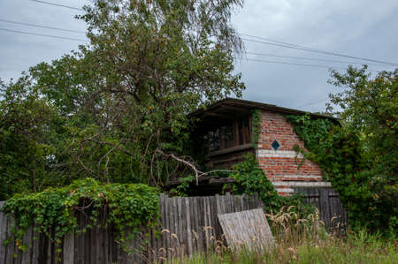 Forgotten old building in little suburb. Early fall trees of green colorsの写真素材
