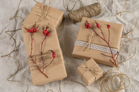 Gifts in craft brown boxes decorated with sprigs of rosehips, lace and jute cord