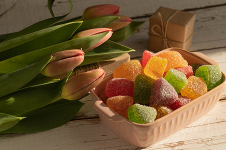 Fruit marmalade multi-colored sprinkled with sugar, tulips, box with a gift in craft brown paper