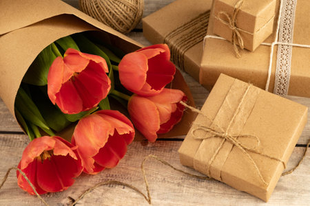 Bouquet of red tulips, gifts in boxes of brown craft paper