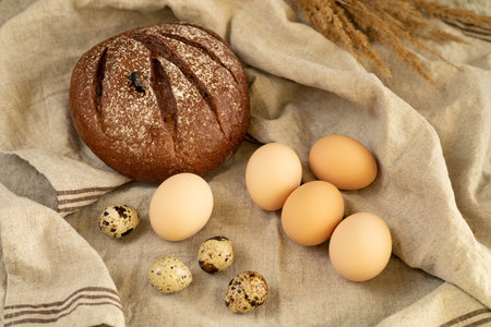 Bread, eggs and ears of wheat on the tablecloth.