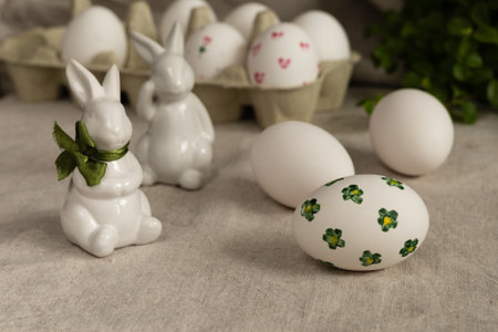 Easter eggs and bunnies with green leaves on tablecloth