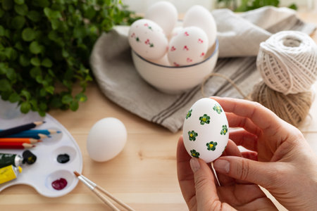 Female hand holding painted easter eggs on wooden table background.の写真素材