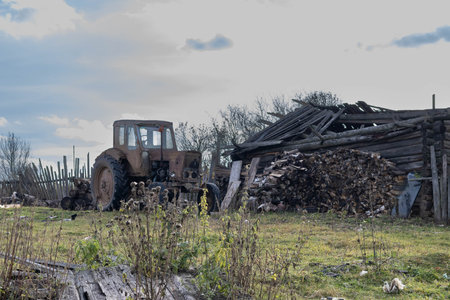 Abandoned old tractor and pile of firewood in the yardの写真素材