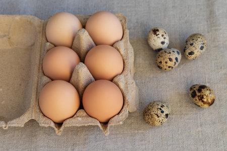 Chicken and quail eggs in a carton on a linen background