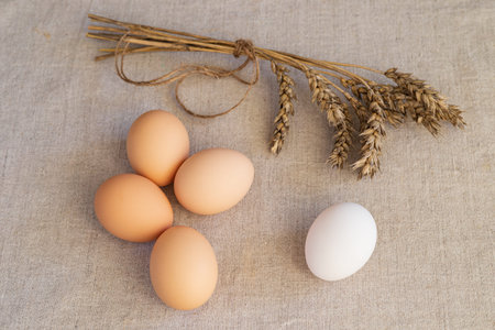 Eggs and ears of wheat on a linen background. Close-up.