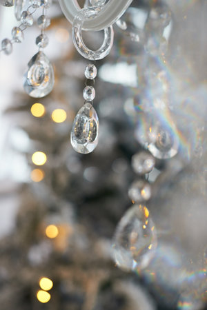 Close up of chandelier decorative crystal or glass pendants and christmas tree on background. Interior design. The concept of New year and Christmas.の写真素材