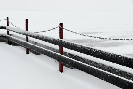 Beautiful winter landscape of Wooden fence with chain on the snow-covered ice of the river. Clean winter season conceptの写真素材