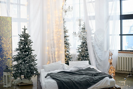 Christmas decorated bright bedroom interior with comfortable bed and Christmas fir trees. Cozy home moment, Happy New Year and Christmas morning conceptの写真素材