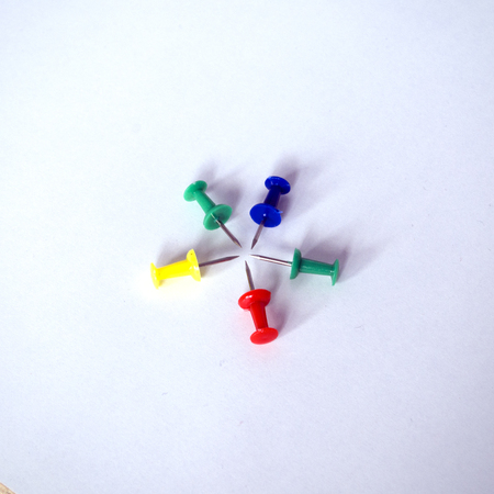 Five colorful pushpins are arranged around and look at each otherの写真素材