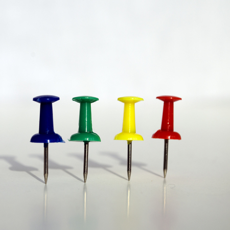 four colorful push pins with shadow on white backgroundの写真素材