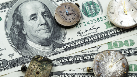 Old clock on the background of money, dollars. Time is money. Money takes time. Money devours time.