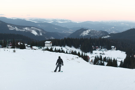 guy on a snowboard down the mountain in a snow-covered winter sunset snow leisure hobbies sportの写真素材