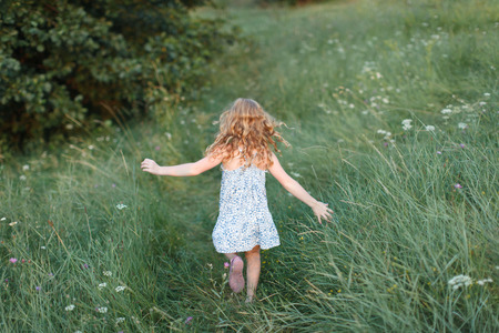 red-haired girl running on a grass dress summer childhood emotionsの写真素材