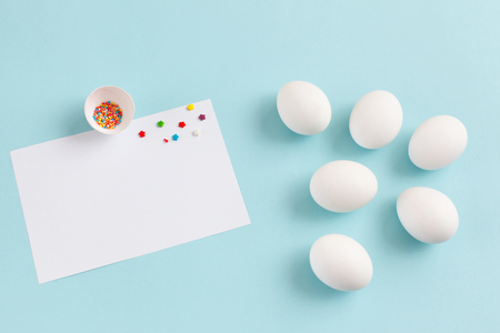 Easter decoration white eggs and broken egg with colored sugar ingredients on a light blue background, white sheet of text, horizontal imageの写真素材