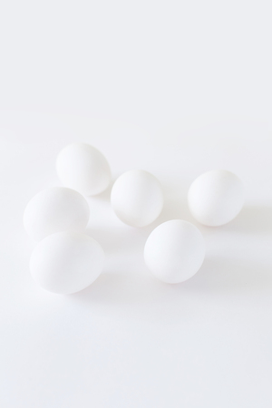 Easter decoration minimalistic white chicken eggs lying on a white background, daylight, vertical imageの写真素材