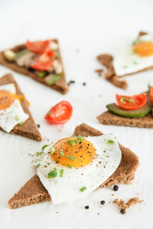 Slices of pie similar to pizza with vegetables, egg and avocado lie on white background, top view. Daylight, space for your text.の写真素材