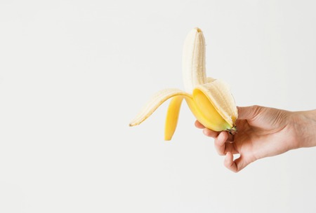The girl is holding a cleaned bitten banana in her hand. Daylight, space for your textの写真素材