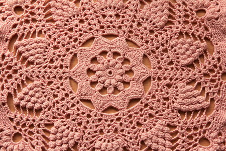 Beautiful closeup pink crochet doily on wooden background