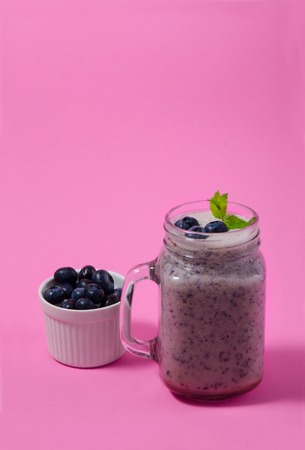 Blueberry smoothie with mint in mason jar glass with berries and mint. Above view on pink table. Healthy food.の写真素材