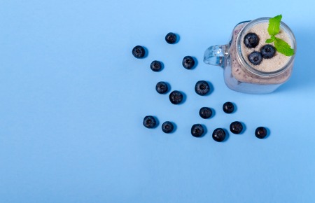 Blueberry smoothie with mint in mason jar glass with berries and mint. Above view on blue table. Healthy food.の写真素材