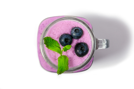 Blueberry smoothie with mint in mason jar glass with berries and mint. Above view on blue table. Healthy food.の写真素材