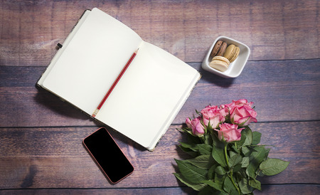 Top view of blank sheet of notebook and red and pink roses flowers on rustic brown wooden table. Copy space.の写真素材