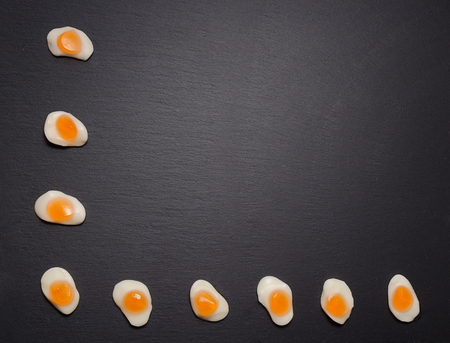Fried eggs candy sweets overhead on dark background. jelly egg candy on black background. Fried egg...