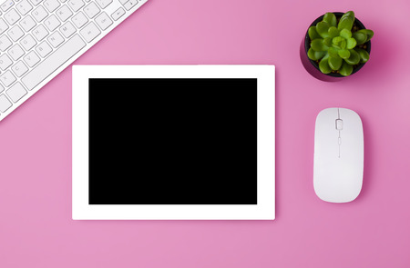 Feminine workplace concept. Items on bright pink background, top view. a tablet on a pink table. Flat lay. Copy space.  White tablet on the pink table with succulent, key board and mouse.の写真素材