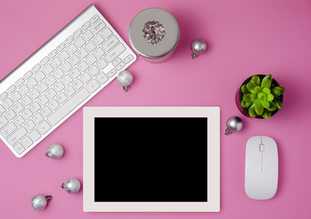 Christmas home office desk with computer, christmas tree, gift, silver decorations. Flat lay, top view, copy space .Feminine workplace concept. Items on bright pink background, top view. A tablet on a pink table. Christmas template. Christmas theme.の写真素材