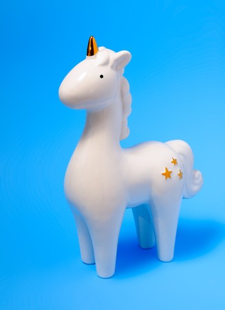 White porcelain unicorn figurine on blue pastel background. White unicorn. Home decoration unicorn.の写真素材