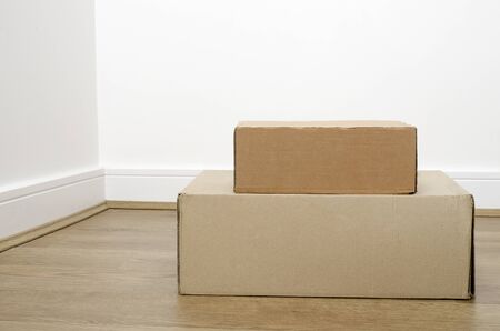 Empty room with stack of cartons: moving house concept. Moving in concept. Two different size boxes  on the laminate floor in the empty room. copy space for the text.の写真素材