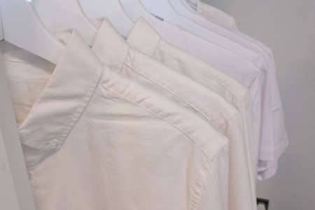 White clothes closeup hanging on white hangersの写真素材