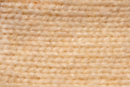 Knitted close-up pattern flat lay natural beige color. Macro knitted top view pattern golden color....