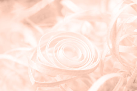 Abstract background close up of shredded wood spiral shape in Peach Fuzz color with copy space