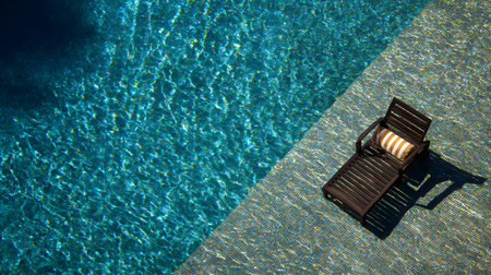 Aerial view of a Beach chair by the swimming pool with sunlight and shadow at a luxury hotel resort. sun loungers and umbrellas. Summer vacation conceptの素材