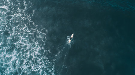 Aerial view of a surfer with a surfboard in the ocean or sea. Top viewの素材