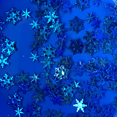 Christmas decorative garland with glimmering cyan snowflakes, silver stars, and blue beads against the indigo backdrop; a square photo for holiday greeting cards and thematic artの写真素材