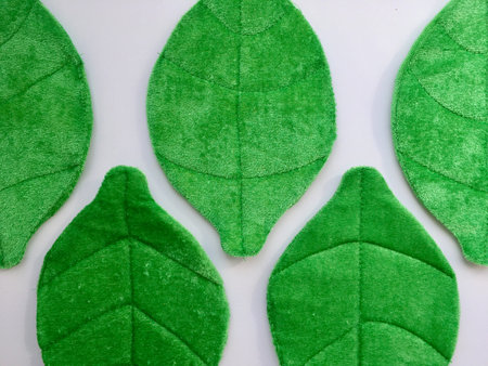 3D plush green leaves forming pattern on white background; horizontal photo of handmade decoration...
