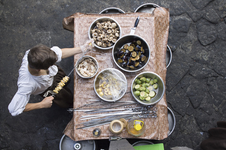Photo of Summer grilling food. Up view of a man stringing vegetables on skewer.の写真素材