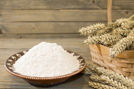 Harvest of wheat spikelets and flour on wooden backgroundの写真素材
