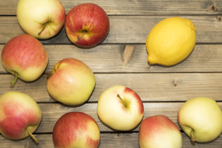 Ripe juicy apples on wooden table, top view. Fresh colorful apples on wooden background. Sweet red apples on the old table. Autumn harvesting. Scattered apples and lemon close up conceptの写真素材